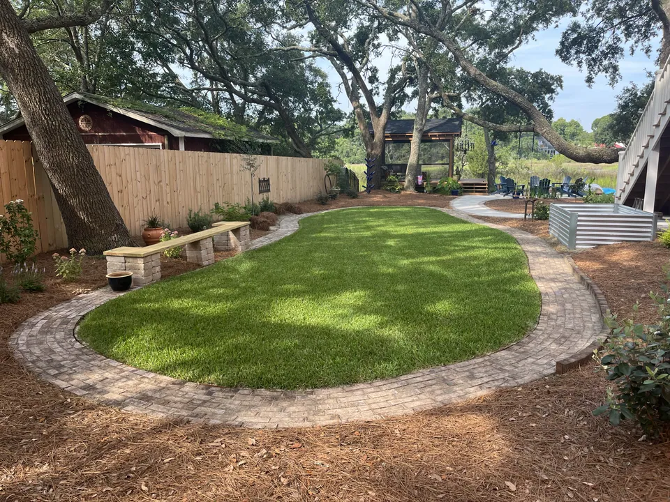 Curved lawn with a stone border in a shaded James Island backyard