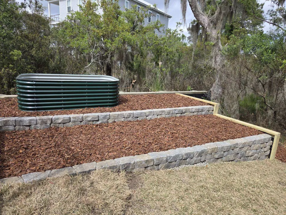 Stone-faced terraced beds filled with mulch beside the home