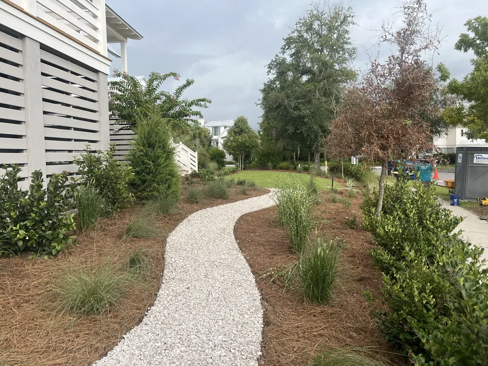 Curved gravel path between planted beds beside the home