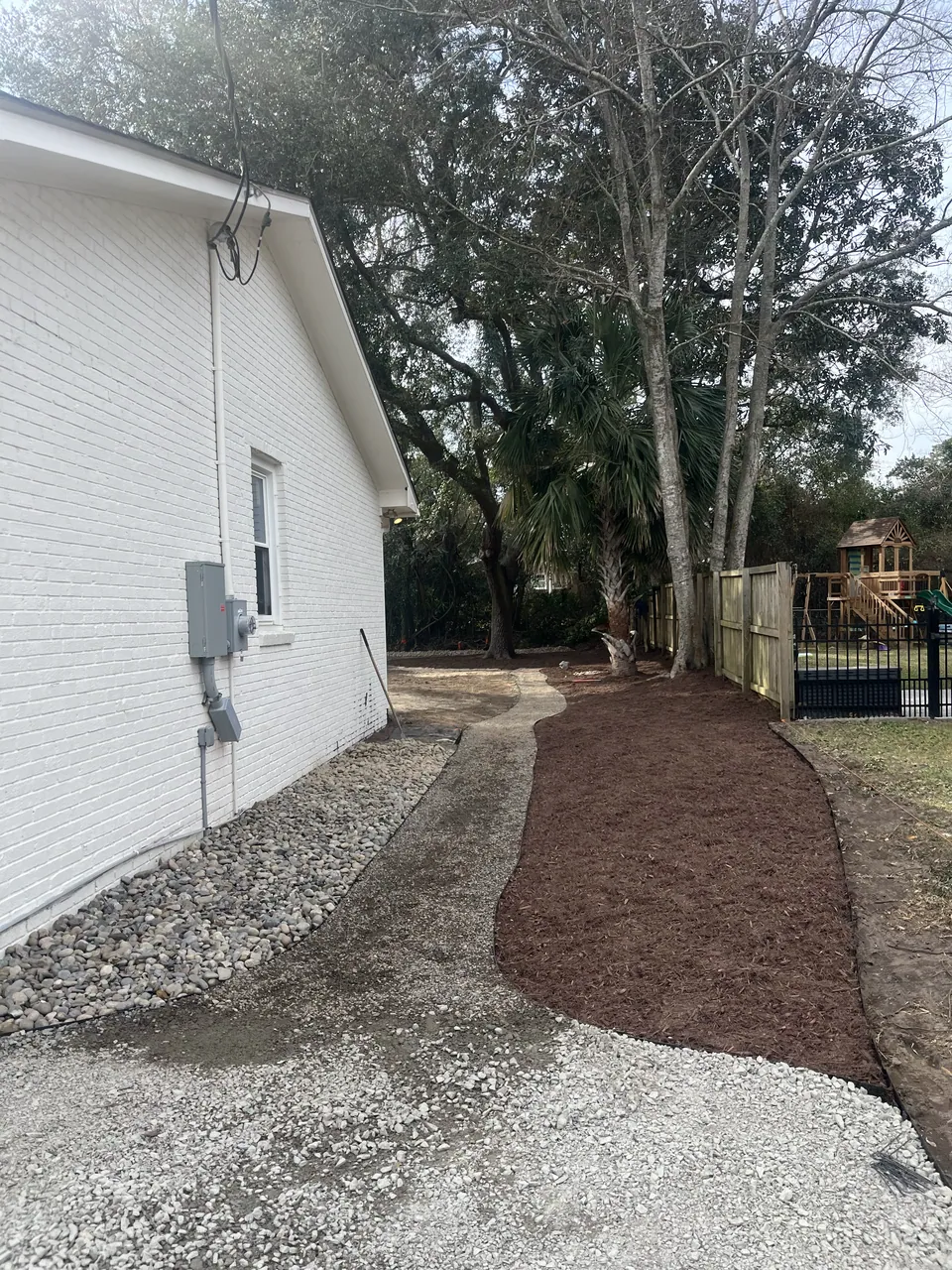 Gravel side area and a mulched planting bed beside the house