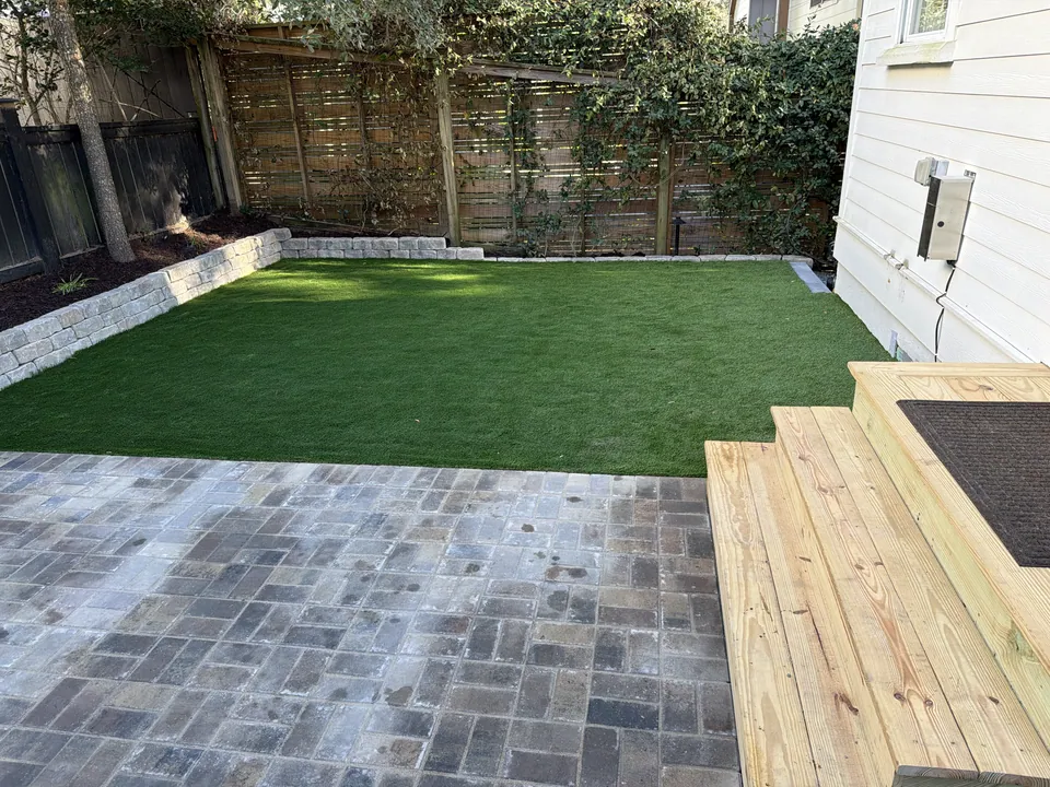 View across the paver patio toward the artificial turf lawn